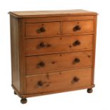 A Victorian stripped pine chest of two short and three long graduated drawers, standing on bun feet,