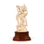 An early 20th century Indian ivory group, a deity with a semi naked woman, mounted on a hardwood