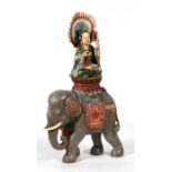 A Chinese polychrome ivory figure of Guan Yin seated on a carved wooden elephant, 31cms (12.25ins)