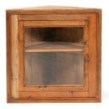 A Victorian pine corner cabinet with glazed door enclosing shelved interior, 77cm (30ins) wide.