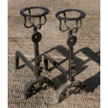 A pair of iron fire dogs with wine bottle holder tops.