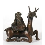 A Chinese bronze group depicting a scholar sat upon a deer, 9.5cms (3.75ins) high.