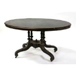 A Victorian ebonised oval loo table, on turned columns and quatrefoil supports, 137cms (54ins)