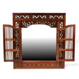 An Eastern hardwood mirror, the mirror enclosed within two pierced doors, 120cms (47.25ins) wide;