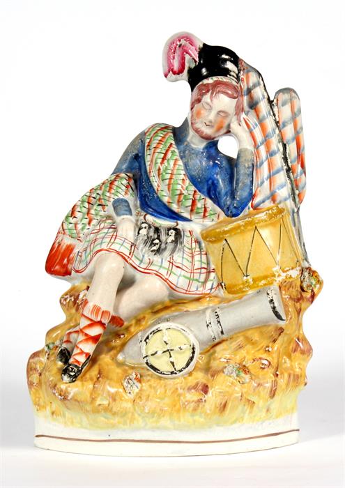 A Victorian Staffordshire figure depicting a Scotsman with a drum and cannon, 28cm (11ins) high.