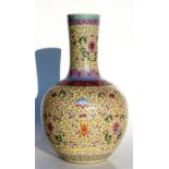 A Chinese famille rose vase decorated with flowers and bats on a pale yellow ground with blue
