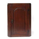 A 19th century mahogany corner cupboard, the panelled door enclosing a shaped shelved interior,