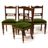 A set of four late 19th century oak dining chairs with upholstered seats and turned front supports.