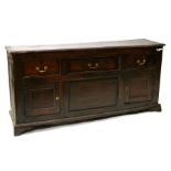 An 18th century oak dresser base with three frieze drawers above cupboards, standing on bracket