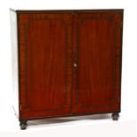A Regency mahogany two-door cupboard with shelved interior, standing on turned feet, 102cms (