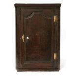 An 18th century oak corner cupboard, the arched panelled door enclosing shelved a interior, 79cms (