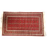 A Persian rug with repeated geometric design on a red ground, 124 by 187cms (48.75 by 73.5ins).