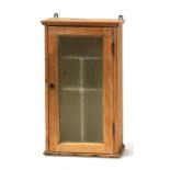 A continental stripped pine wall cupboard, with frosted glass door enclosing a shelved interior,