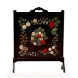 A late 19th / early 20th century ebonised firescreen, decorated with textile flowers (the material