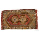 A small Caucasian rug with two central guls on a red ground, 53 by 88cms (21 by 34.75ins).