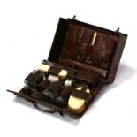 A leather travelling grooming set with silver topped jars and ivory brushes.