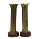 A matching pair of trench art shell case vases elaborately decorated with a gentleman and a lady.
