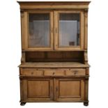 A large stripped pine continental dresser, the glazed top above three frieze drawers with