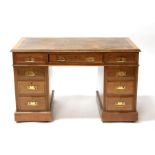 An early 20th century oak pedestal desk with an arrangement of nine drawers, on plinth base,