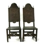 A pair of Italian walnut hall chairs, with pressed leather seats and backs, decorated with cherubs