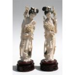 Two early 20th century Chinese ivory figures depicting robed women holding flowers, 26cms (10.25ins)