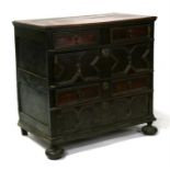 A Jacobean oak chest with two short and three long geometric moulded drawers, standing on bun