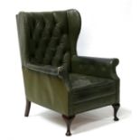 A green leather buttoned wing back armchair.