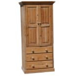A modern pine cupboard, the pair of panelled doors enclosing a shelved interior, above three long