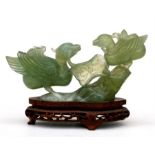 A Chinese green hardstone group depicting two birds and a lily pad, mounted on a pierced hardwood