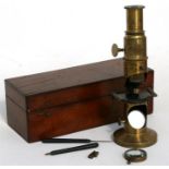 A late 19th century brass student's microscope, in mahogany case, 20cms (8ins) high.