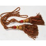 A pair of red, gold and green braid curtain tie-backs