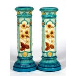 A pair of late 19th century Burmantoft jardiniere stands, decorated in relief with flowers, 62cm (