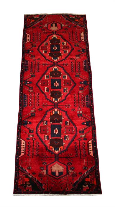 A Tabriz woollen hand made runner with three central medallions, on red ground, 290 by 100cms (114