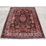 A Persian Kashmar hand knotted woollen rug with flowers, foliage and figures within an animal and