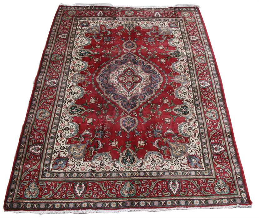 A Tabriz carpet with central medallion on a red ground 325 by 245cm