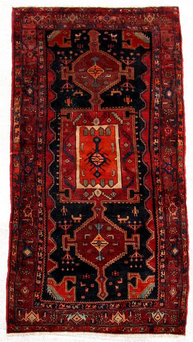 A Kurdish hand knotted Kordi runner with geometric medallions on a red ground, 325 by 150cms (128 by