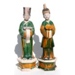 A pair of Chinese Ming Dynasty glazed pottery figures of attendants, wearing long flowing green