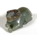 A carved green jade like figure in the form of a recumbent water buffalo, 6.5cm (2.5ins) long.