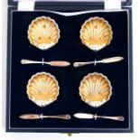 A cased set of shell form silver plated salts.