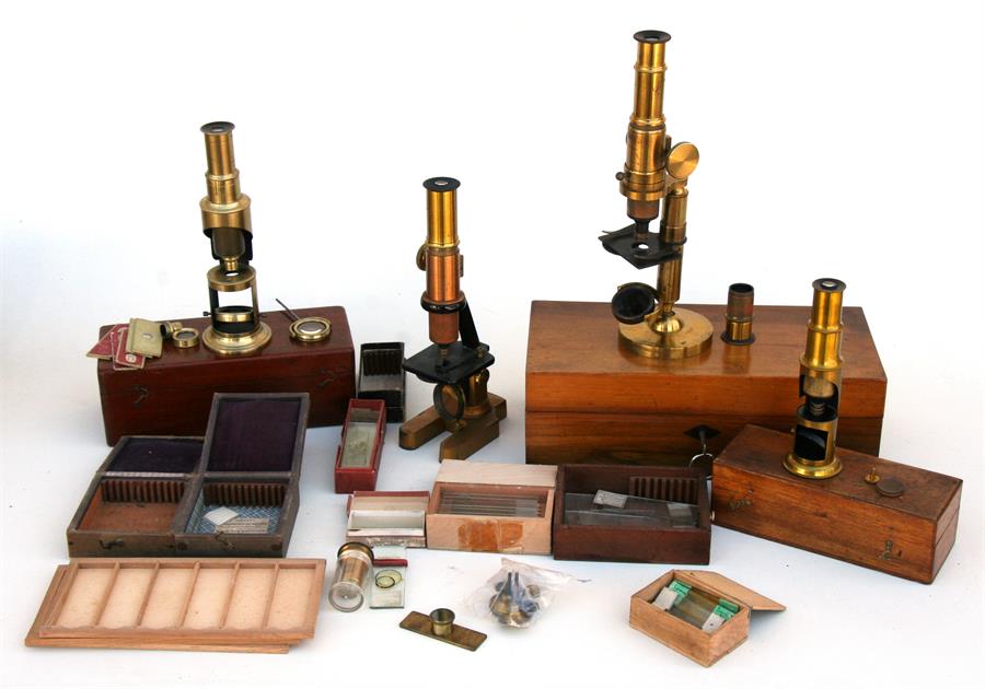 A lacquered brass microscope in a walnut box; two student microscopes; another microscope and a