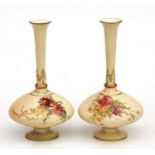 A pair of Royal Worcester blush ivory pedestal vases decorated with flowers and gilt highlights,