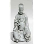 A Chinese blanc de chine style figure of a seated scholar wearing long flowing robes and holding a
