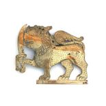 An Eastern brass plaque in the form of a stylised lion holding a sword, 14cms (5.5ins) high.