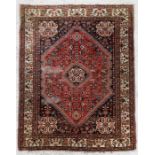 A Persian rug with central medallion within a foliate border, on red ground, 106 by 153cms (41.75 by