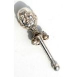 A white metal baby's rattle in the form of Humpty Dumpty, 14cms (5.5ins) high.