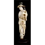 A late 19th century ivory carving depicting a robed lady carrying a basket and holding flowers,