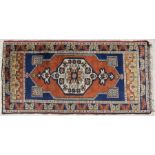 A small Persian rug with central medallion within a foliate border, on a burnt orange ground, 57