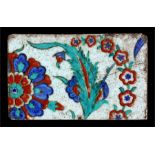 A Persian / Iznic tile decorated with flowers in enamel colours, 17 by 11cms (6.25 by 4.25ins) (a/