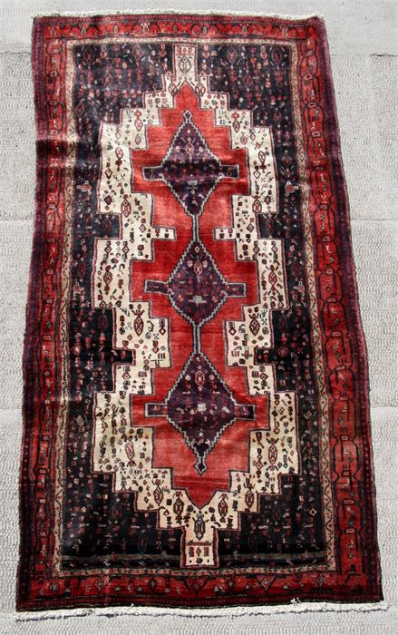 A Persian Kordi runner with geometric design on a red ground, 290 by 130cms (114 by 51ins).