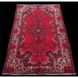 A Persian Feridan woollen hand made rug with stylised flowers and geometric borders, on red